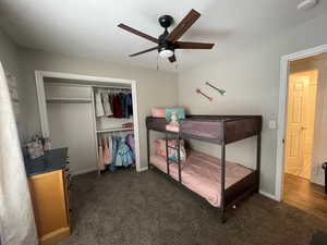 Carpeted bedroom with ceiling fan, a textured ceiling, and a closet