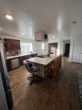 Kitchen featuring a center island, a textured ceiling, appliances with stainless steel finishes, and LVP flooring