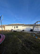 Rear view of house featuring a trampoline and a lawn