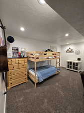 Bedroom with dark carpet and a textured ceiling