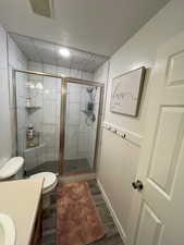 Bathroom featuring vanity, LVP flooring, toilet, and a shower with shower door