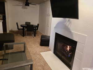 Carpeted living room with ceiling fan and a tiled fireplace