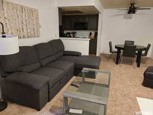 Carpeted living room with ceiling fan and crown molding