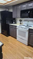 Kitchen with light hardwood / wood-style floors and black appliances