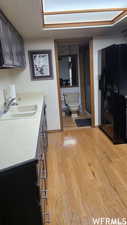 Kitchen featuring sink, black fridge with ice dispenser, and light hardwood / wood-style flooring