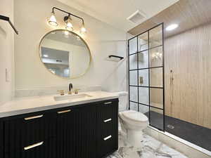 Bathroom with toilet, vanity, and tiled shower