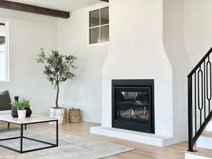 Living room with a fireplace, hardwood / wood-style floors, and beam ceiling