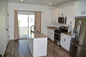 Kitchen with a center island with sink, sink, white cabinetry, and stainless steel appliances