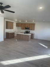 Kitchen featuring a kitchen island with sink, light hardwood / wood-style flooring, ceiling fan, and stainless steel appliances