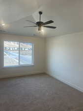 Carpeted empty room with ceiling fan and vaulted ceiling