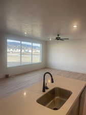 Kitchen with a textured ceiling, ceiling fan, sink, light hardwood / wood-style flooring, and dishwasher