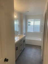 Bathroom featuring a tub, vanity, and a textured ceiling