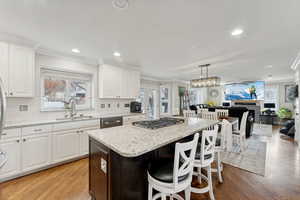 Kitchen featuring sink, pendant lighting, light hardwood / wood-style flooring, a center island, and white cabinetry