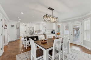 Dining space featuring hardwood / wood-style flooring, an inviting chandelier, and ornamental molding