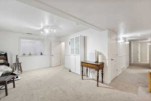 Interior space with light colored carpet and a textured ceiling