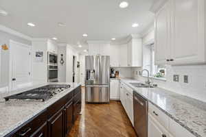 Kitchen featuring white cabinets, crown molding, sink, hardwood / wood-style flooring, and appliances with stainless steel finishes