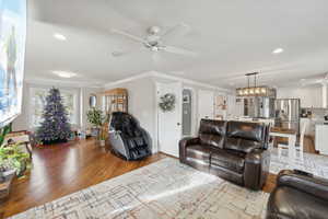 Living room featuring light hardwood / wood-style floors, ceiling fan, and ornamental molding