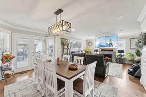 Dining area featuring hardwood / wood-style floors, ceiling fan with notable chandelier, a fireplace, and crown molding