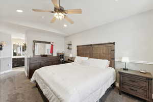 Bedroom with carpet, connected bathroom, vaulted ceiling, and ceiling fan