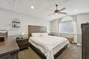 Carpeted bedroom featuring ceiling fan and vaulted ceiling