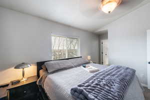 Carpeted bedroom featuring ceiling fan and lofted ceiling