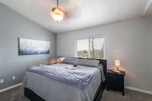 Bedroom with dark carpet and lofted ceiling