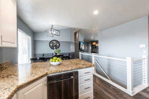 Kitchen featuring light stone countertops, pendant lighting, dark hardwood / wood-style floors, and white cabinetry