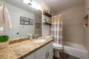 Full bathroom with hardwood / wood-style flooring, vanity, shower / tub combo, and toilet