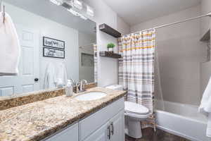 Full bathroom with toilet, shower / tub combo with curtain, vanity, and hardwood / wood-style flooring