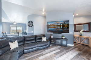 Living room featuring hardwood / wood-style floors, lofted ceiling, and an inviting chandelier