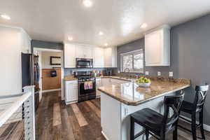 Kitchen featuring white cabinets, appliances with stainless steel finishes, kitchen peninsula, and dark hardwood / wood-style floors