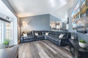 Living room featuring a wealth of natural light, hardwood / wood-style floors, lofted ceiling, and an inviting chandelier