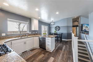 Kitchen featuring sink, black dishwasher, dark hardwood / wood-style floors, a textured ceiling, and white cabinets