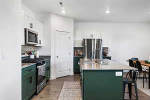 Kitchen featuring stainless steel appliances, sink, dark hardwood / wood-style floors, white cabinetry, and green cabinets