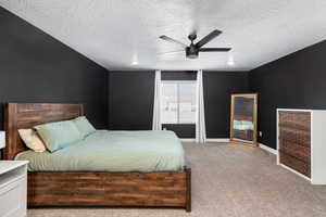 Bedroom with ceiling fan, light carpet, and a textured ceiling