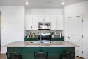 Kitchen featuring a kitchen breakfast bar, white cabinetry, and appliances with stainless steel finishes