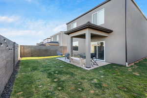 Rear view of property with a yard and a patio