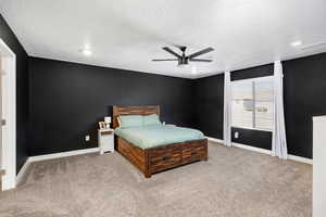 Bedroom featuring a textured ceiling, ceiling fan, and light carpet