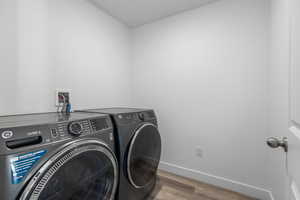 Clothes washing area with washer and dryer and light hardwood / wood-style floors