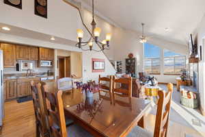 Dining area with light hardwood / wood-style flooring, ceiling fan with notable chandelier, and sink