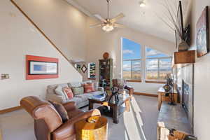 Carpeted living room with ceiling fan and a towering ceiling