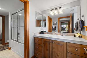 Full bathroom with vanity, toilet, and bath / shower combo with glass door