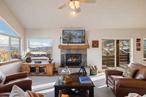 Living room featuring carpet floors, ceiling fan, and a tiled fireplace