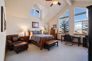 Bedroom with beamed ceiling, light colored carpet, high vaulted ceiling, and ceiling fan