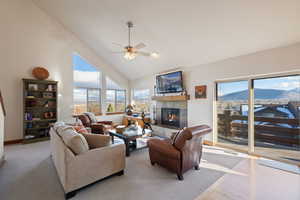 Living room with ceiling fan, light wood-type flooring, a fireplace, and high vaulted ceiling