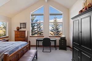 Bedroom with light colored carpet and vaulted ceiling