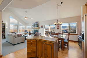 Kitchen featuring ceiling fan with notable chandelier, high vaulted ceiling, light hardwood / wood-style flooring, and a wealth of natural light