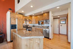 Kitchen featuring light wood-type flooring, stainless steel appliances, a kitchen island, and sink