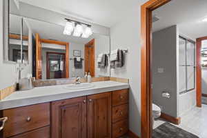 Full bathroom with vanity, toilet, and bath / shower combo with glass door