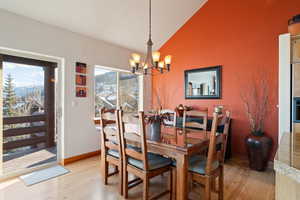 Dining room with light hardwood / wood-style floors, lofted ceiling, and a chandelier